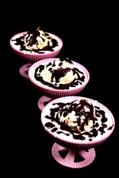 On a black background three bowls in which the white chocolate covered dessert