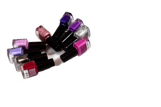 On a white background nine bottles with colored nail polish vydozheny opposite each other