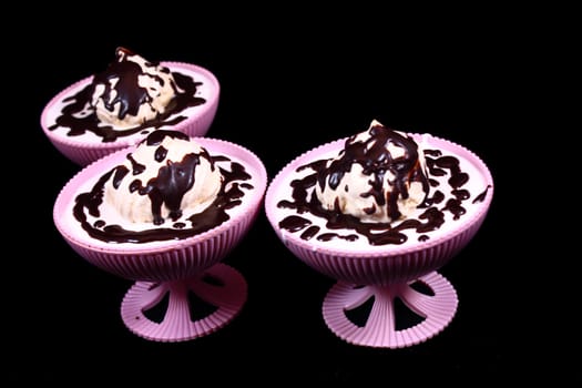 In three pialas dessert with chocolate on a black background