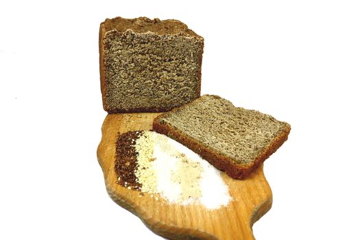 On a wooden board is brown bread, slice of bread, flax seeds, sesame seeds, sugar, salt, yeast