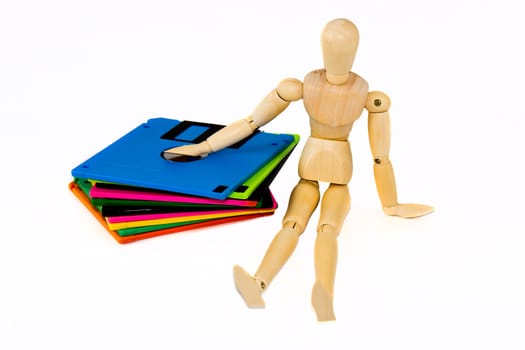 wooden manikin sitting near diskettes isolated