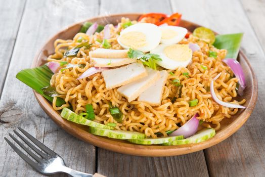 Dry Instant Noodle, Malaysian style maggi goreng mamak or spicy dry curry instant noodles. Asian cuisine, ready to serve on wooden dining table setting. Fresh hot with steamed smoke.