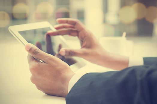 Close-up of Indian male hands touching digital tablet, formal businessman with cup of coffee on table.