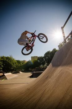 Bmx rider performing a bar spin to a quarter pipe ramp on a skatepark.