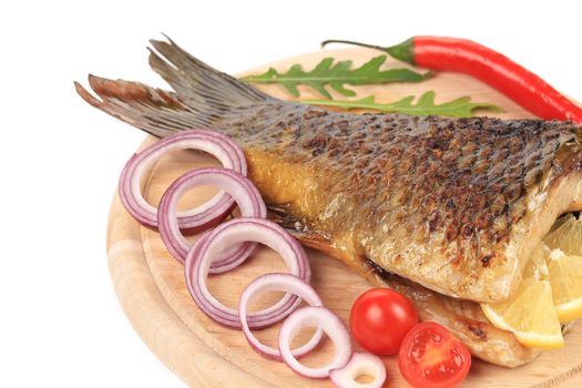 Grilled carp with lemon and tomatoes. Isolated on a white background.
