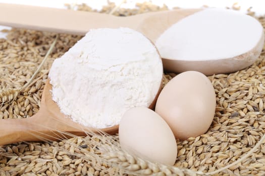 Spoon with flour on wheat background.