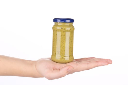 Hand holds italian sauce Pesto. Isolated on a white background.