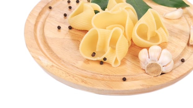 Italian pasta shells on a wood plate. Whole background.