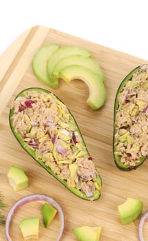 Avocado salad with tuna on cutting board. Isolated on a white background.
