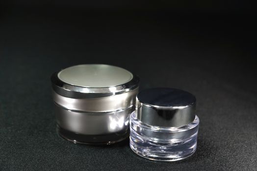 two different shaped acrylic cream pot, on black scene,shallow focus