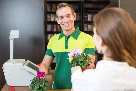 Cashier or shopkeeper in flower shop or retail store serving a customer