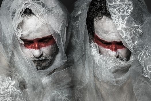 man covered with white lace veil, mask of red makeup