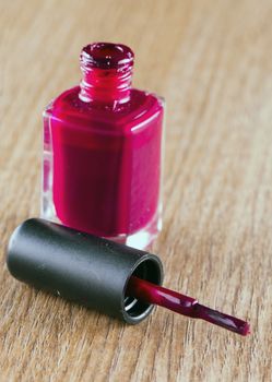 Red nail polish over a wooden background