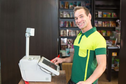 Cashier at cash register in shop or store with books in background