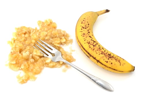 Spotty ripe banana with mashed flesh and fork, isolated on a white background
