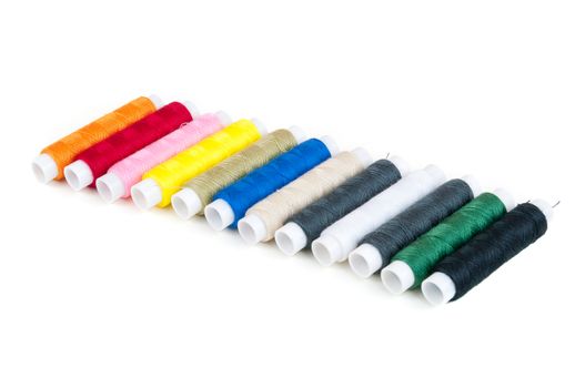 Colored spools of threads in a row isolated on white background