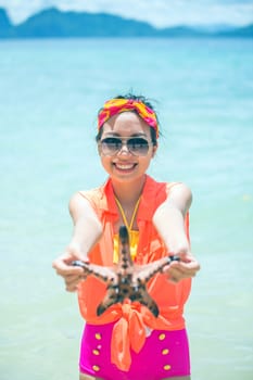 Young woman shows starfish during holiday at tropical island