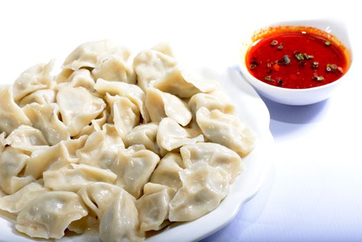 Chinese Food:  boiled dumplings with sauce on a white background