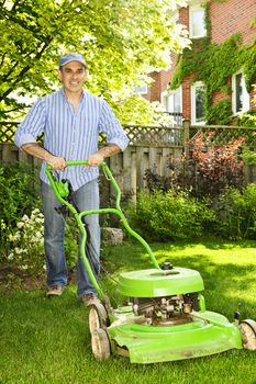 Man with lawn mower in landscaped backyard