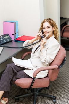 Thoughtful business woman on phone taking notes in office workstation