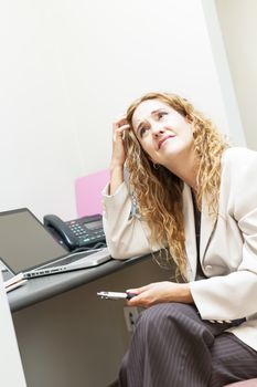 Businesswoman worried in office workstation looking up