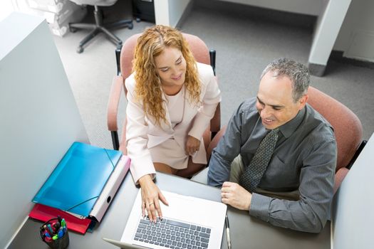 Man and woman sitting at desk with computer in office