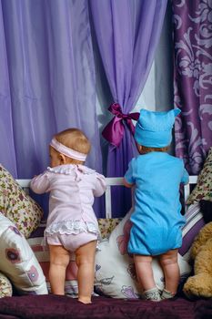 Brother and sister in the nursery are on the cradle turned to the window waiting for the arrival of parents