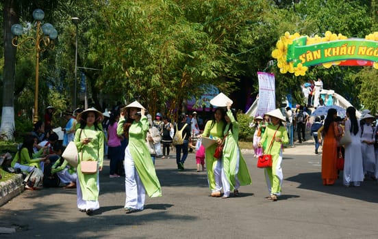 HO CHI MINH, VIETNAM- MARCH 8: Group of young girl in Vietnamese traditional dress - conical hat, ao dai- walking in park on Aodai festival, they so charming, sweet, beautiful, Viet Nam, March 8, 2014