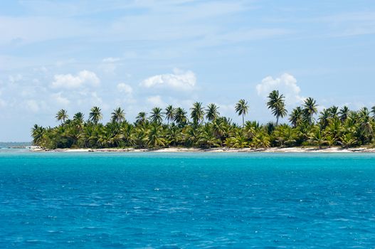 Empty Caribbean island with a nice beach and green palms. The picture of the beach is taken from a boat on sea.