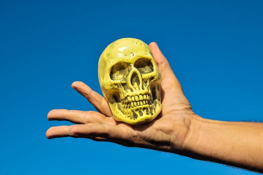 Vintage Old Skull and Human Hand over a Blue Sky