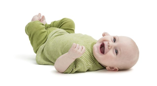 happy baby in green clothing lying on his back. isolated on white background
