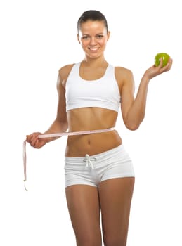 young athletic woman holding a green apple and measuring waist, isolated on white background