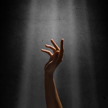 woman's hand reaches for the light rays, conceptual image of striving for freedom