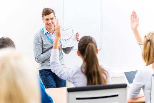 young teacher man talking with students in the classroom