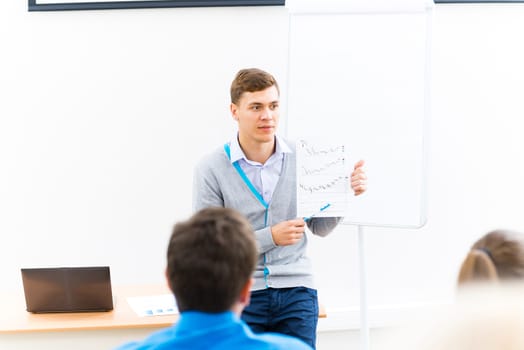 young teacher man talking with students in the classroom