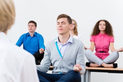 young man, meditating with closed eyes, group meditation