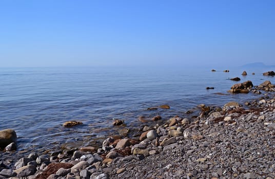 Sea beach of pebbles and stones near the calm sea