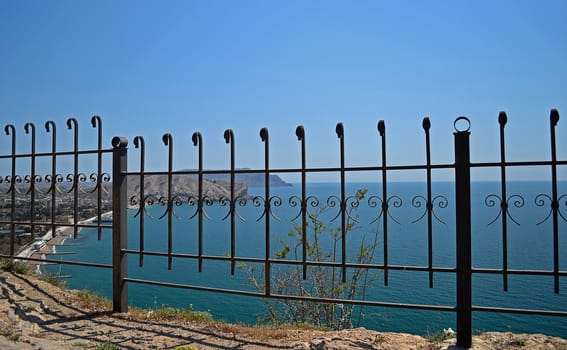 Black metal fence near the blue sea