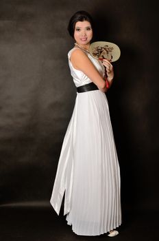 Chinese female wearing long white dress. Asian girl holding fan in her hand, girl with gentle smile.