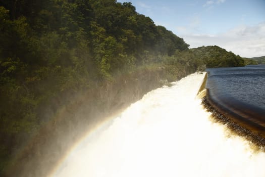 Dam on mountain river. Expanded water from the waterfall.