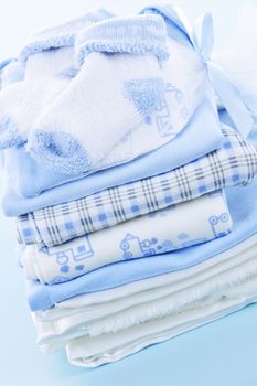 Stack of blue infant clothing for baby shower