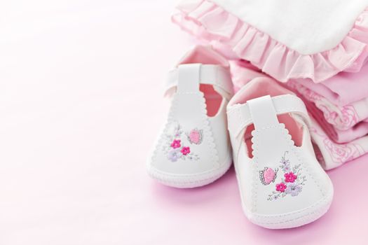 Infant girl clothing and shoes for baby shower on pink background