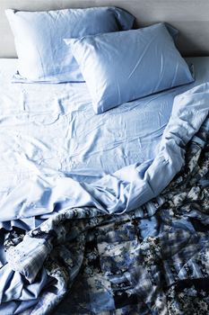 Unmade messy bed with wrinkled sheets from above