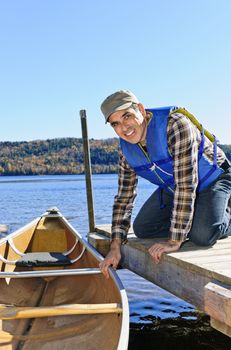 Man holding canoe at dock on Lake of Two Rivers, Ontario, Canada