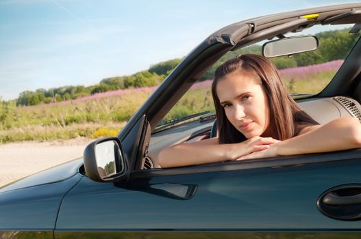 Outdoor shot of beautiful brunette female in car