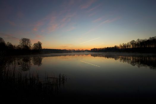 Sunrise over the lake and a flying plane