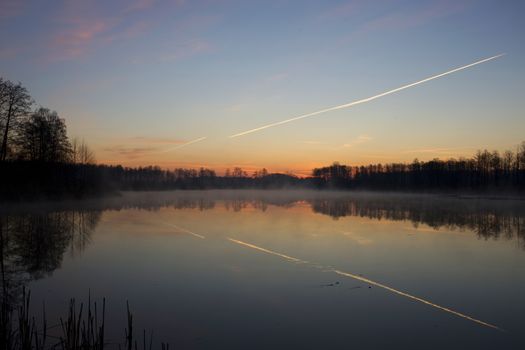 Sunrise over the lake and a flying plane