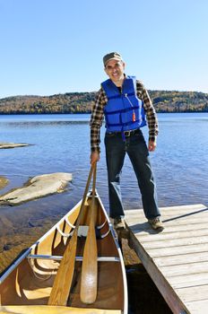 Man standing on dock with canoe on Lake of Two Rivers, Ontario, Canada