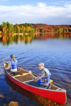 People canoeing on scenic lake in fall, Algonquin park, Canada