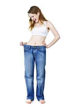 Excited fit young woman in loose old jeans after losing weight isolated on white